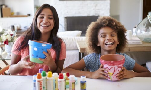 girls painting flower pots and laughing