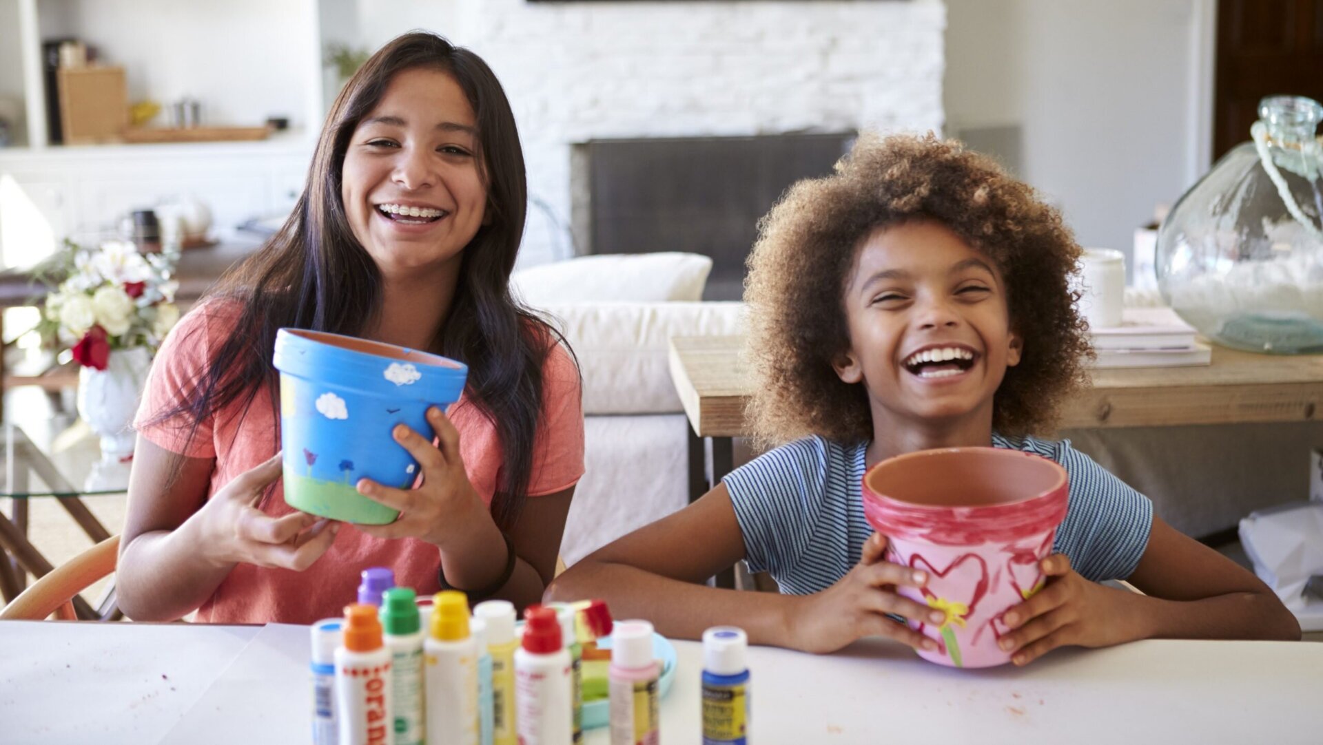 girls painting flower pots and laughing