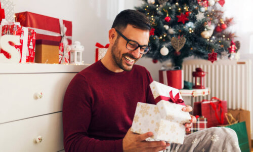 Man smiles while opening a Christmas gift