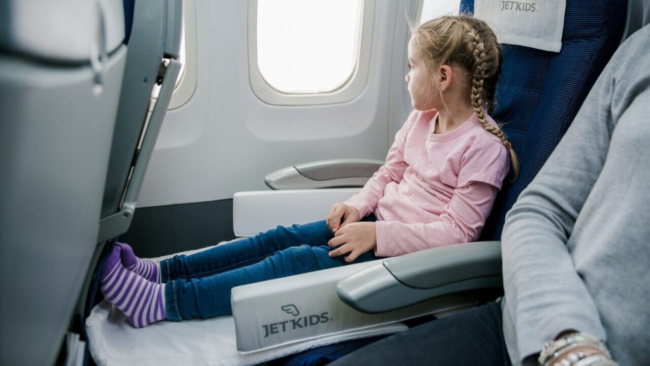 child in JetBox looking out airplane window