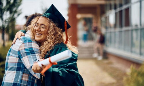 Happy graduate embraces father after graduation ceremony.