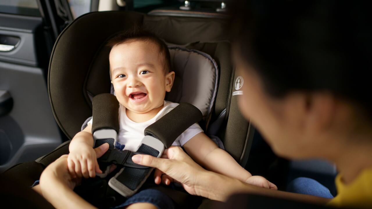 baby being fastened into a car seat