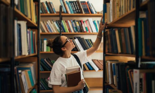 woman reaching for books on a bookshelf