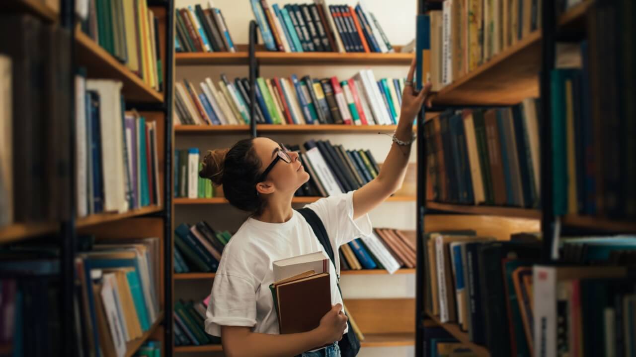 woman reaching for books on a bookshelf